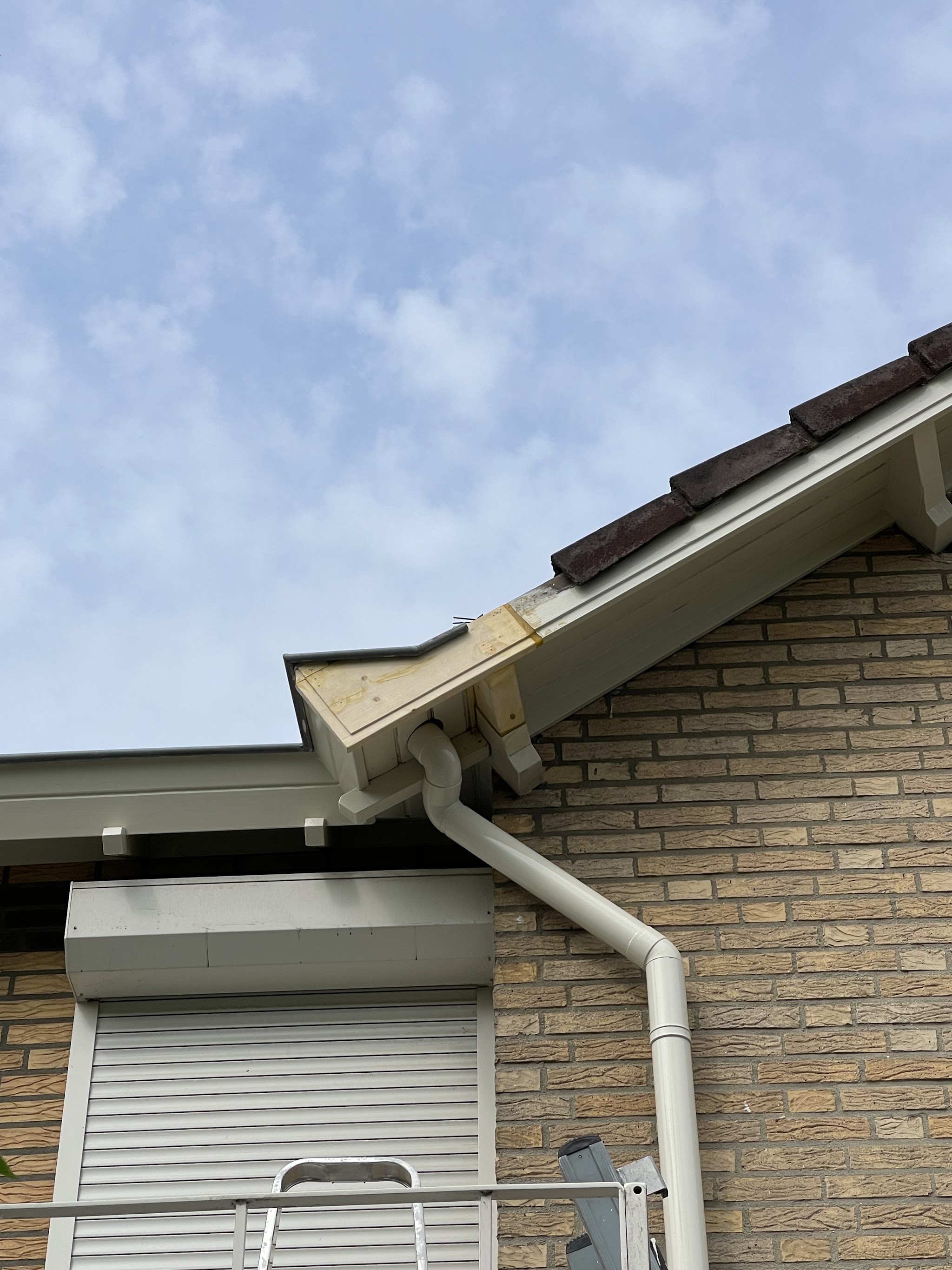 Nieuwe witte boeidelen en dakgoot aan een bakstenen woning