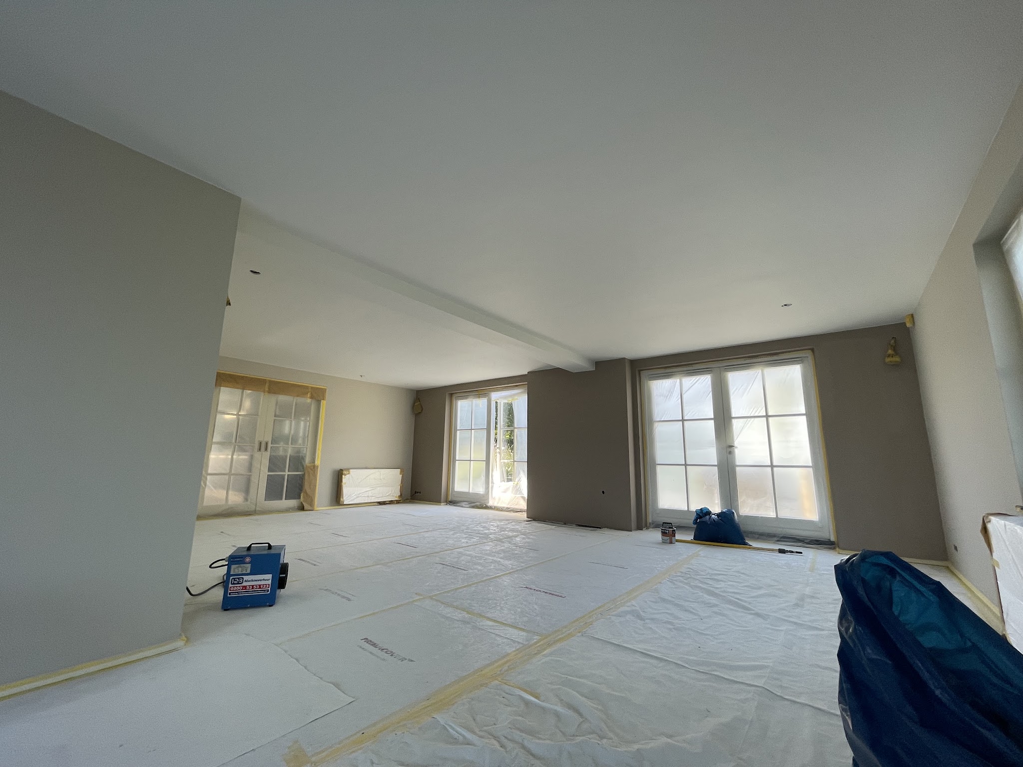 Lege woonkamer afgeplakt met folie, klaar voor spuitwerk