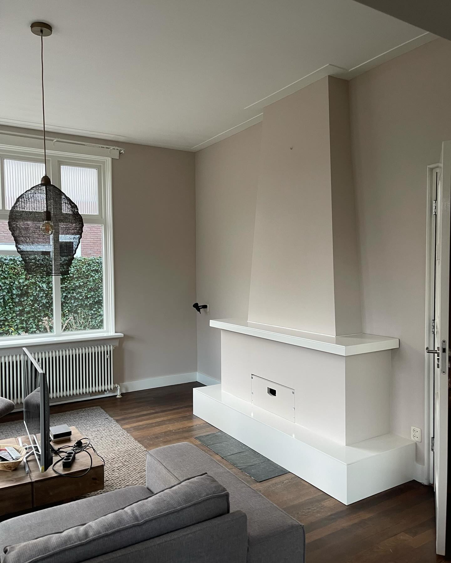Geschilderde woonkamer van een jaren 60 woning met lichte wanden en een schouw
